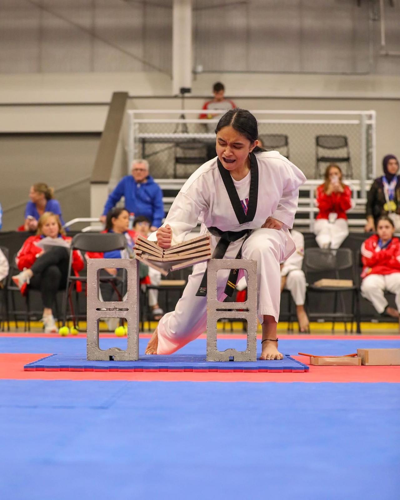 Siona demonstrates focus, precision, and strength during a board-breaking event.