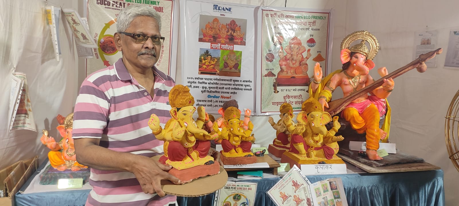 Craftsman presenting a yellow Ganesha idol at an eco-friendly exhibition stall