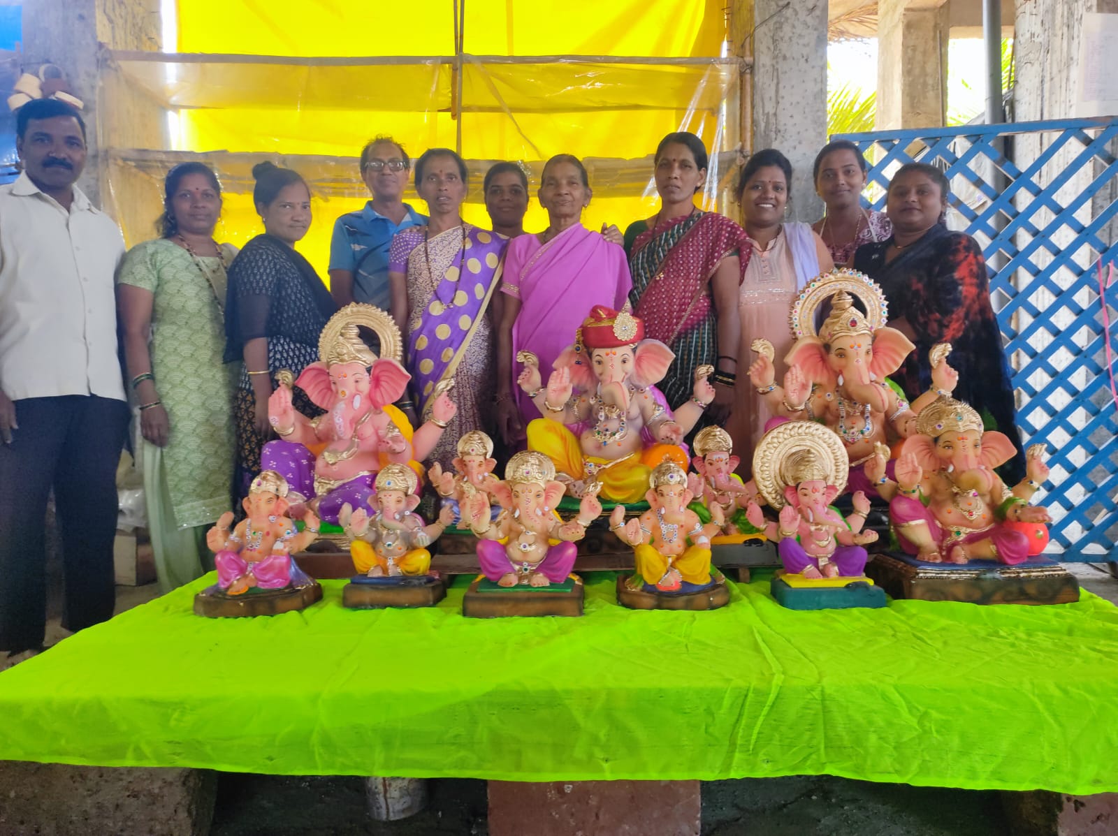 Group of artisans standing behind a display of colorful handcrafted Ganesha idols